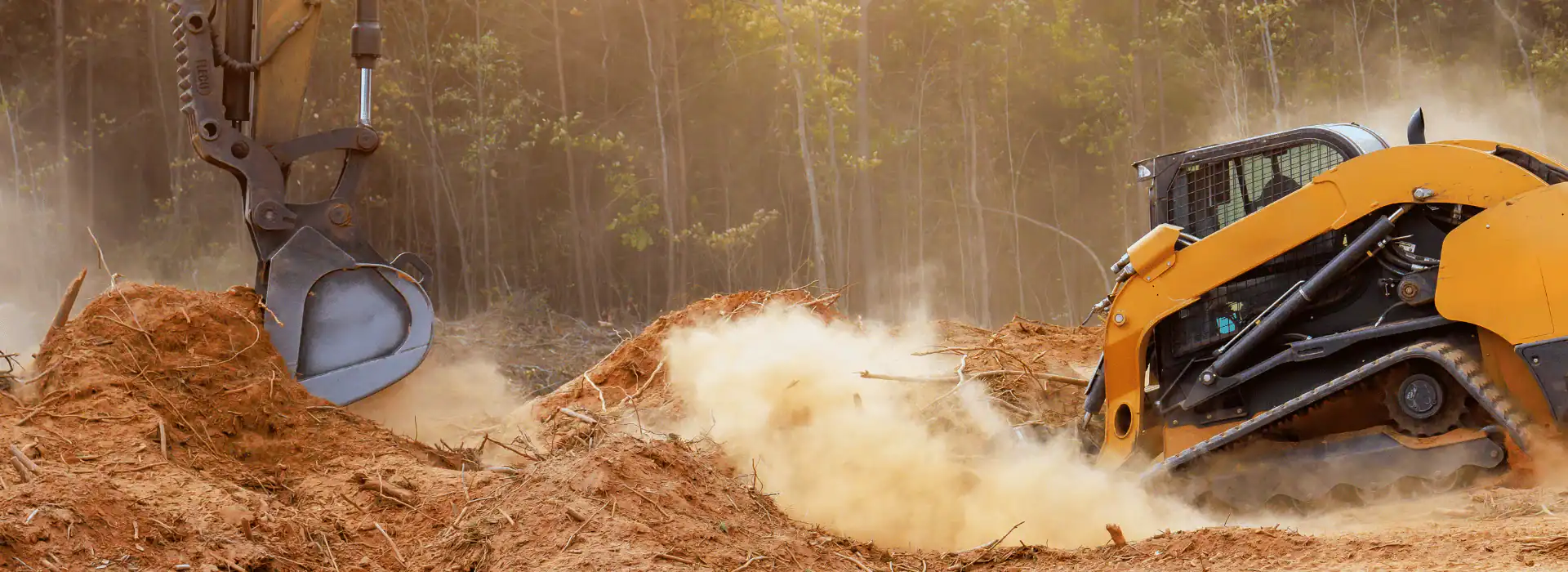 A yellow bulldozer and an excavator, operated by a skilled Excavation Contractor Suffolk County, work together stirring up dust and dirt on a NY construction site, with trees in the background.
